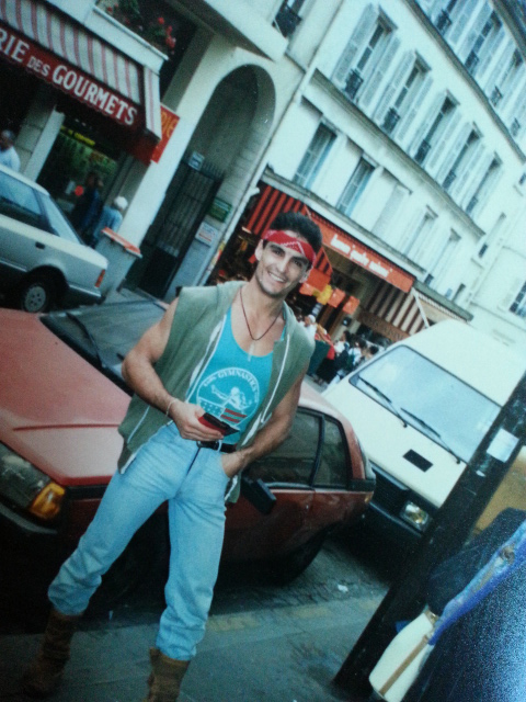 Cliff Simon in the 1980s, standing on Rue Lepic (outside his first apartment in Paris) dressed in typical '80s attire: leather boots, headband, leather necklace.